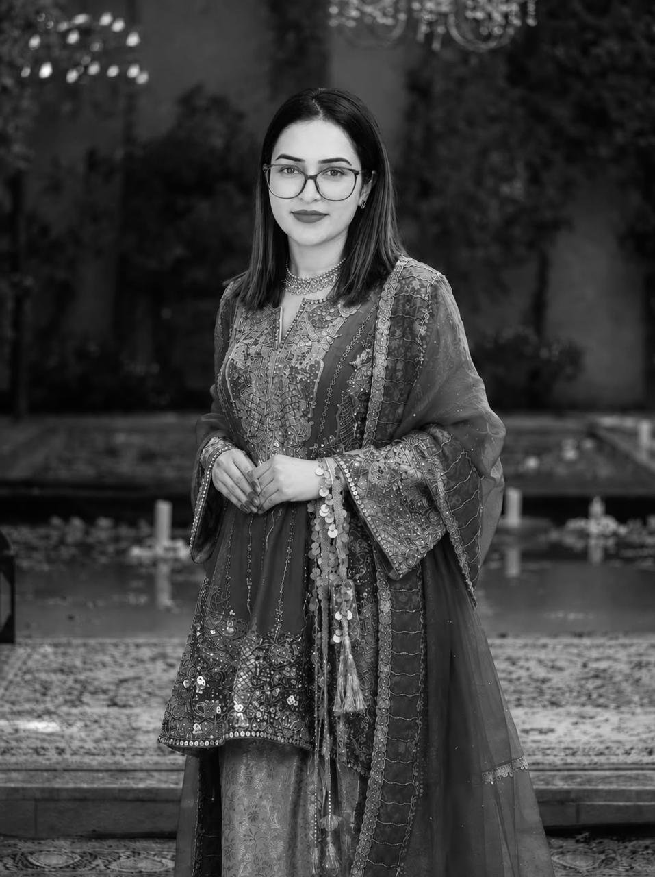 Black-and-white portrait of a woman in glasses wearing an embroidered kurta with a sheer dupatta