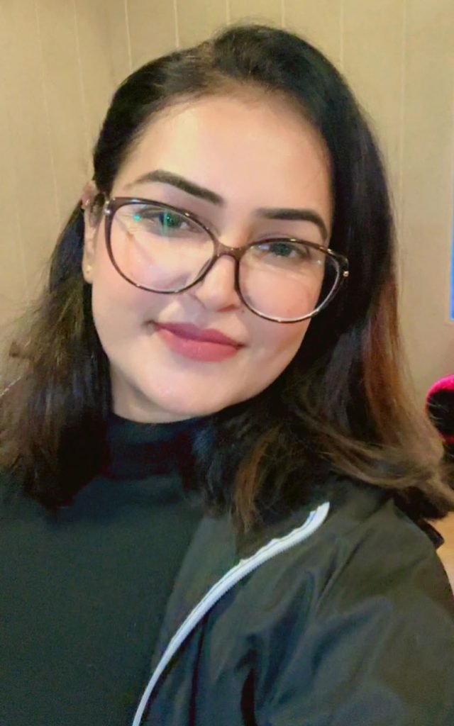 Close-up portrait of a woman in large glasses wearing a black high-neck top and jacket